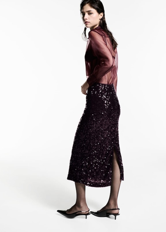 Une tenue avec une jupe midi pailletée de couleur bordeaux.