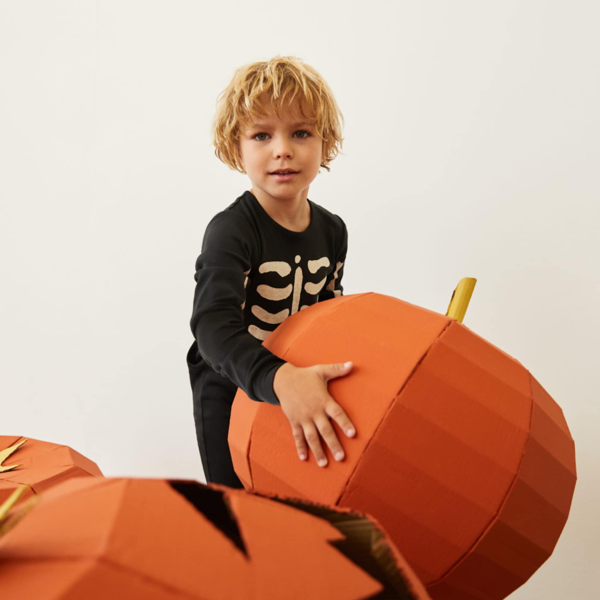 Niño disfrazado jugando con calabazas