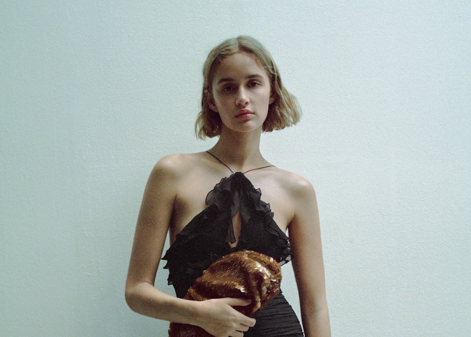 Woman wearing a dark winter guest dress with spaghetti straps