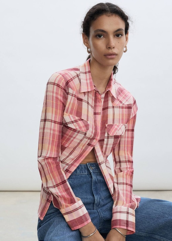 Seated woman wearing a casual look with a printed blouse and jeans.