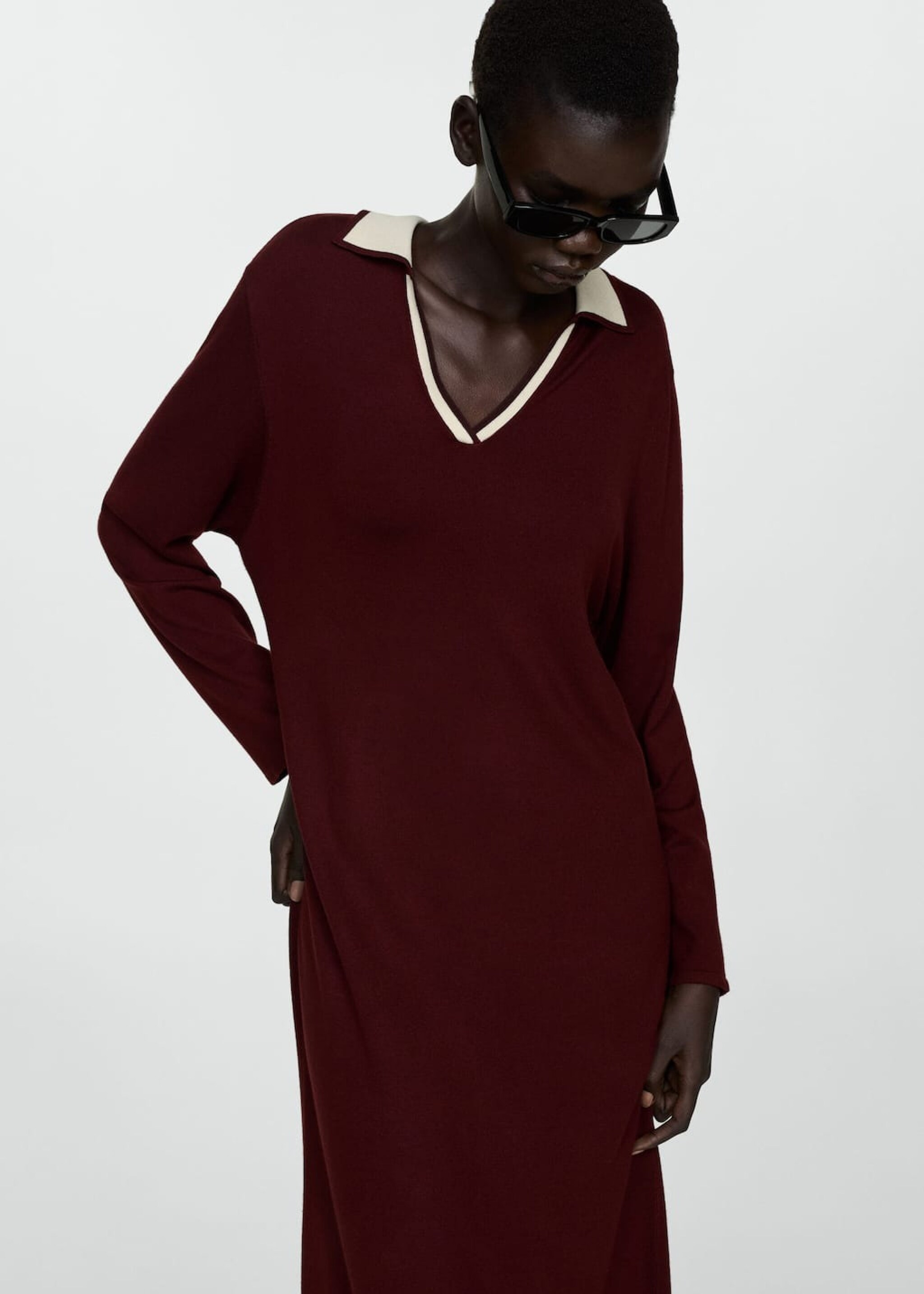 Seated girl wearing a black knitted dress and small handbag