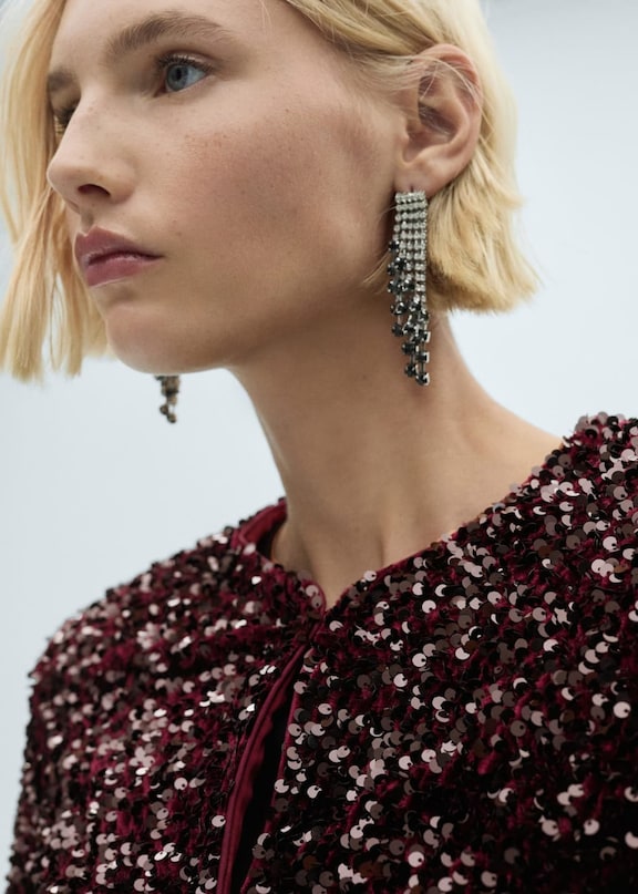 Une tenue avec une jupe à paillettes et des boucles d'oreilles argentées.