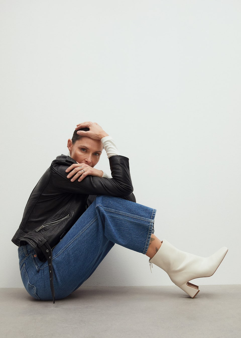 Mujer sentada con botas blancas y vaqueros