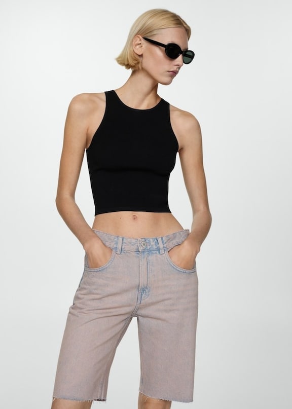 Girl wearing a festival outfit with ripped denim shorts and a black top.