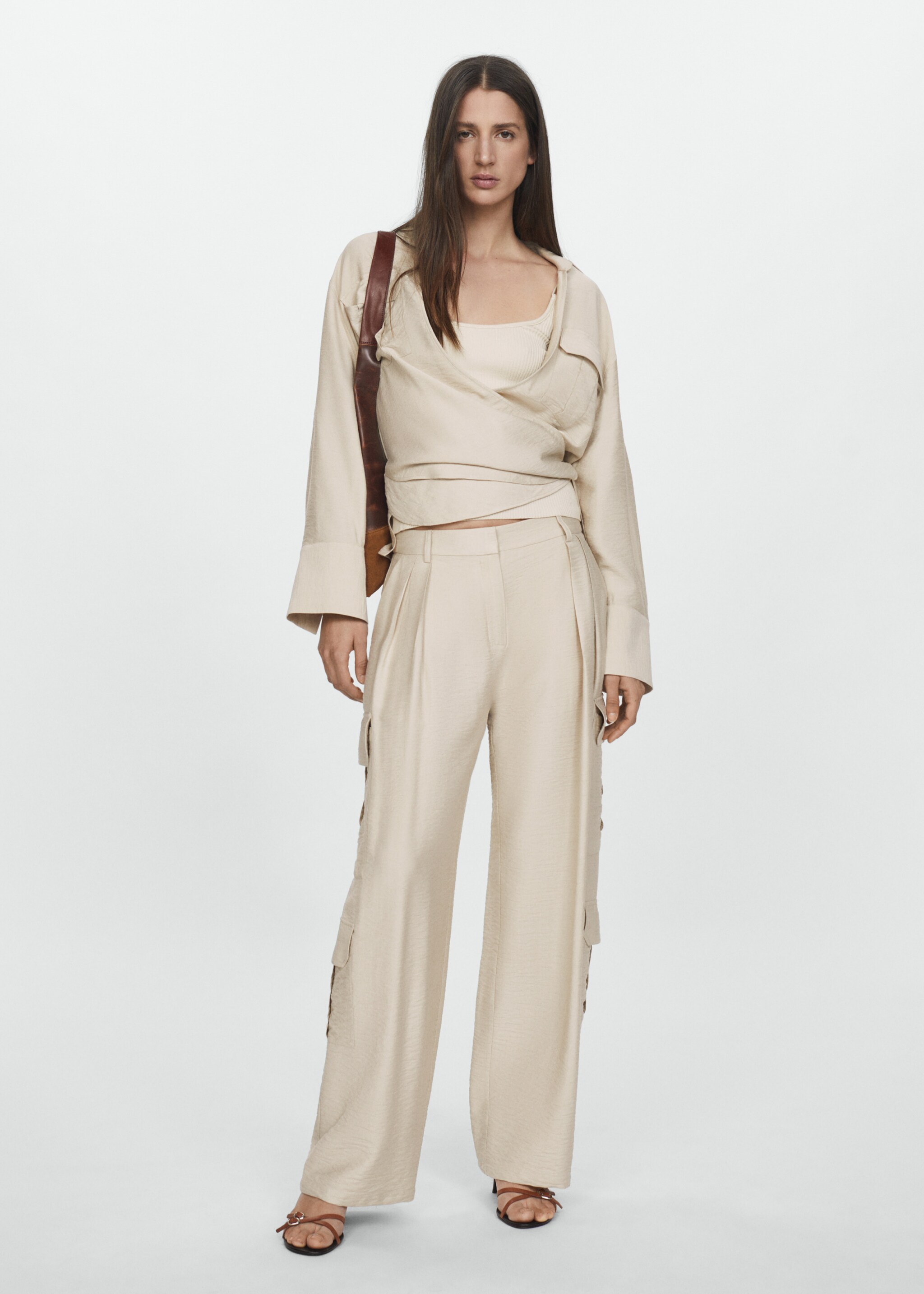 Woman combining beige cargo trousers with an oversize shirt.