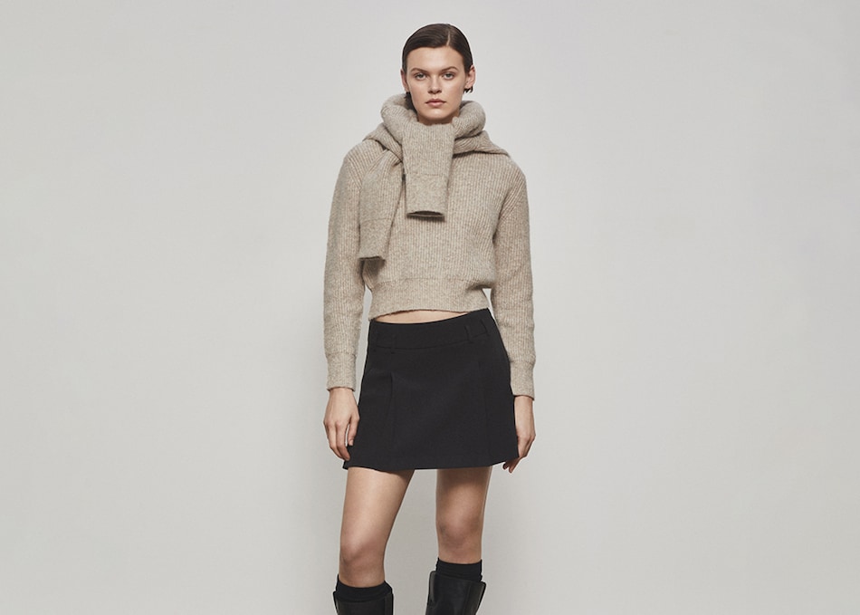 Woman wearing a casual outfit of brown skirt and jumper.