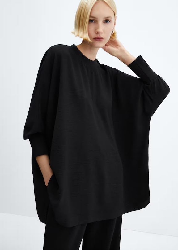 Mujer usando en outfit oversize con un jersey y pantalones negros